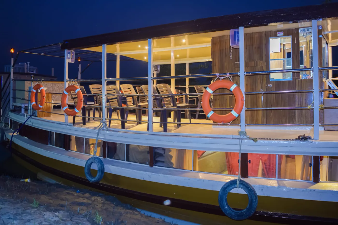 Max Adventures houseboat glowing warmly in the evening with the open deck visible